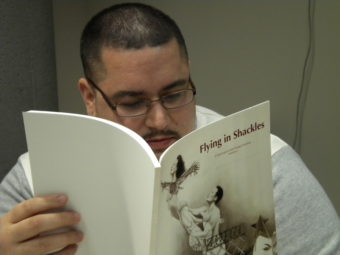 UAS student Marcos Galindo reads an issue of the Flying University literary journal. Galindo is one of the 15 former and current inmates of Lemon Creek Correctional Center to write contributions to the journal. (Photo by Kevin Reagan/ KTOO)