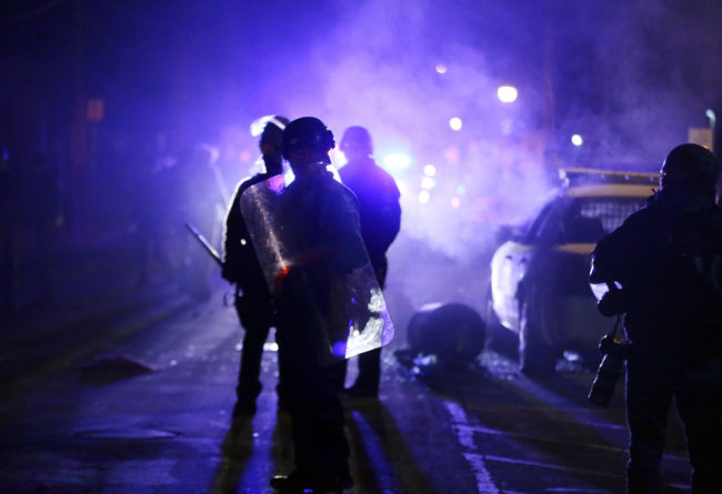 Police officers watch protesters as smoke fills the streets of Ferguson, Mo., on Nov. 25, 2014. Charlie Riedel/AP