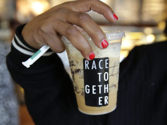 Larenda Myres holds an iced coffee drink with a "Race Together" sticker on it at a Starbucks store in Seattle. Starbucks baristas will no longer write "Race Together" on customers' cups starting Sunday. (Photo by Ted S. Warren/AP)