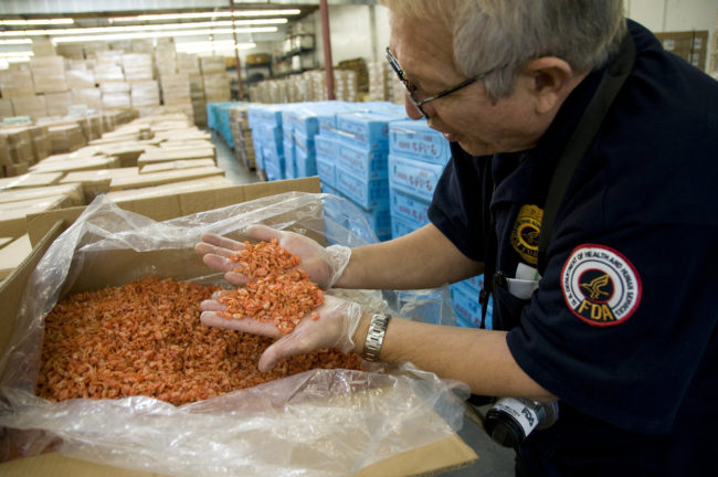 An FDA field inspector in Los Angeles checks imported shrimp, February 2009. More than a dozen federal agencies play a part in keeping food from making Americans sick. Critics say that leads to a lack of coordination, a patchwork of rules and holes in the system. FDA