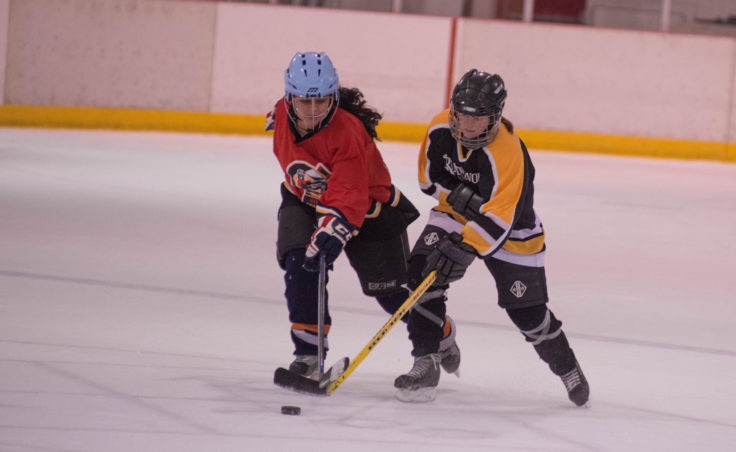 Kensington’s Christy Hartman and Rendezvous’ Suzanne McGee battle for a loose puck in playoff action during a Juneau Adult Hockey Association contest. (Photo by Steve Quinn)