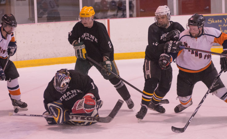 Players from Island Pub and Thane crowd around goalie Thomas Mckenzie who looks for the loose puck in playoff action during a Juneau Adult Hockey Association contest. (Photo by Steve Quinn)