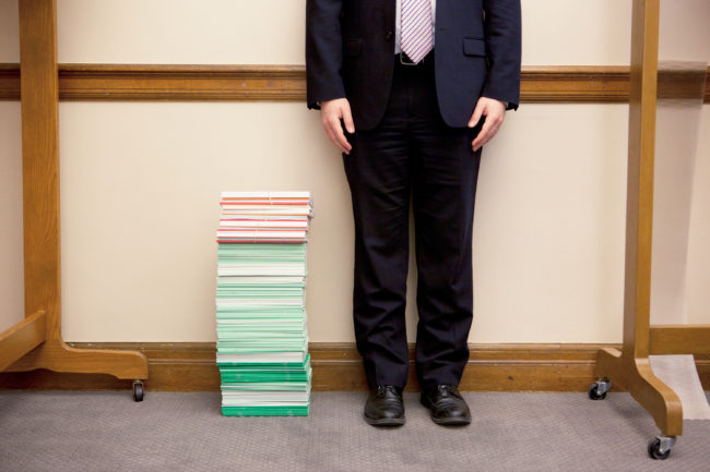 The stack of amicus briefs filed as of April 9 reached past the knee of NPR legal affairs intern Anthony Palmer. The briefs cost, on average, an estimated $25,000 to $50,000. (Photo by Emily Jan/NPR)