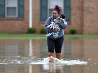 Simone Wester and her 7-month old son Jeremiah walk through the flood waters outside her apartment building at the Guardian Court Apartments in Louisville, Kentucky, on Friday. (Photo by Timothy D. Easley/AP)
