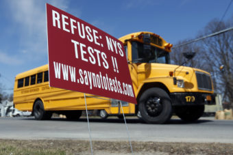 A school bus passes a sign encouraging parents to have their children opt out of state tests in Rotterdam, N.Y. (Photo by Mike Groll/AP)
