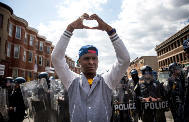 A man makes a heart shape with his hands during a peaceful protest near the CVS pharmacy that was set on fire on Monday in Baltimore. (Photo by Andrew Burton/Getty Images)
