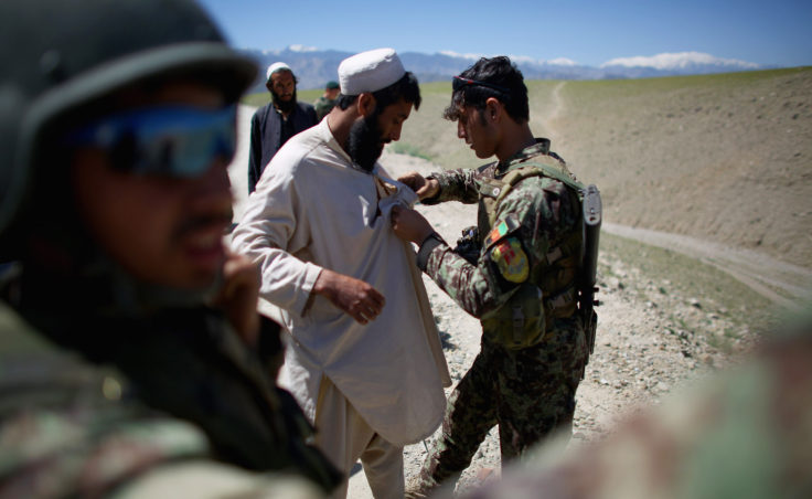 An Afghan army soldier frisks a man who claims to be an Afghan policeman. After questioning, and producing an ID, he was released. None of the 10,000 U.S. military personnel are present as the Afghan army fights in the eastern province of Nangahar, a notorious Taliban bastion near the border with Pakistan. (Photo by David Gilkey/NPR)