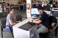 Christopher Avila, a National Guardsman, works with a customer in March during a shift at T-Shirt Mart in Point Loma, Calif. He says he lost an IT job because the guard needed him for two straight weekends, followed quickly by two weeks of training on new equipment. (Photo by Katie Schoolov/KPBS)