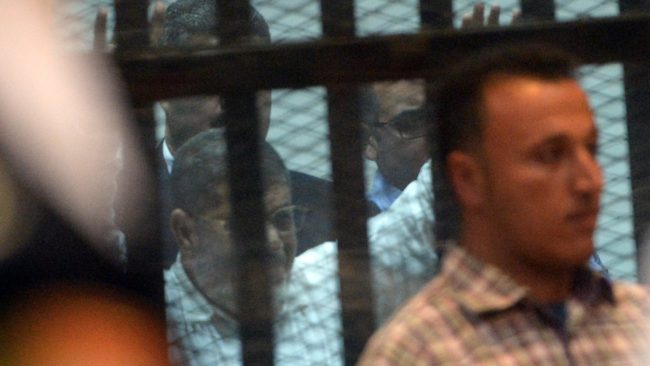 Egypt's former President Mohammed Morsi gestures from the defendants' cage during his trial in Cairo on Tuesday. An Egyptian court sentenced the ousted leader to 20 years in prison for abuses of protesters. (Photo by Mohamed El-Shahed/AFP/Getty Images)