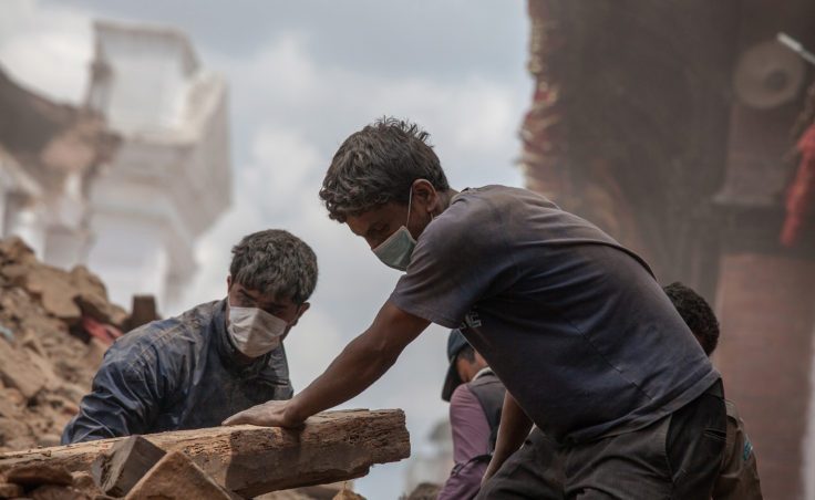 Volunteers clear debris of a collapsed temple