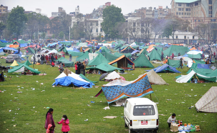 Nepalese people gather near temporary shelters set up in open areas of an army ground in Kathmandu.