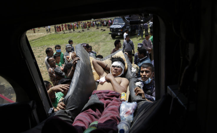 Nepali soldiers carry an injured man to an Indian air force helicopter as they evacuate victims from Trishuli Bazar to Kathmandu airport. (Photo by Altaf Qadri/AP)