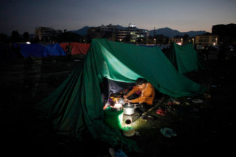 A Nepalese man cooks food inside a tent as people relocate to open ground from fears of earthquake tremors in Kathmandu, Nepal, on Monday evening. (Photo by Niranjan Shrestha/AP)