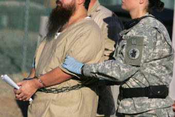 A shackled detainee is transported by guards, including a female soldier, at Camp Delta detention center, Guantanamo Bay U.S. Naval Base, Cuba, in this photo from December 2006. (Photo by Brennan Linsley/AP)