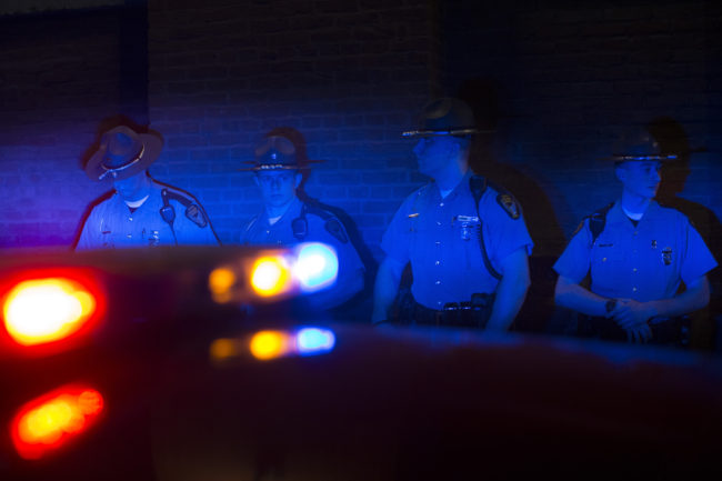 Police officers are illuminated by patrol car lights during a protest against the acquittal of Michael Brelo on Saturday in Cleveland.