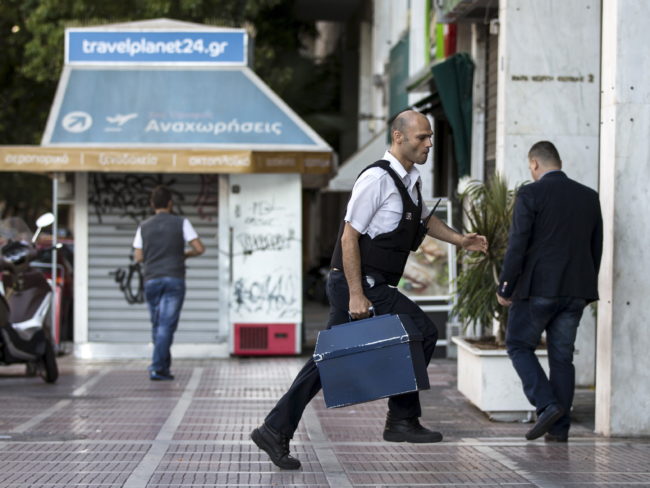 A security worker brings money to a National Bank branch in Athens on Sunday. Greeks have been withdrawing euros in anticipation of a possible default on the country's debt payments early next week. Marko Djurica/Reuters