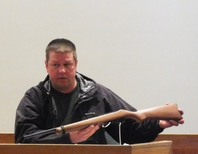 Juneau Police Officer Jeffrey Brink holds up 10-22 Ruger rifle that is similar to the one used to kill Simone Kim on Aug. 4, 2006.  Convicted murderer Jason Coday sawed off both the barrel and the stock of the rifle that he obtained from Rayco Sales. (Photo by Matt Miller/KTOO)