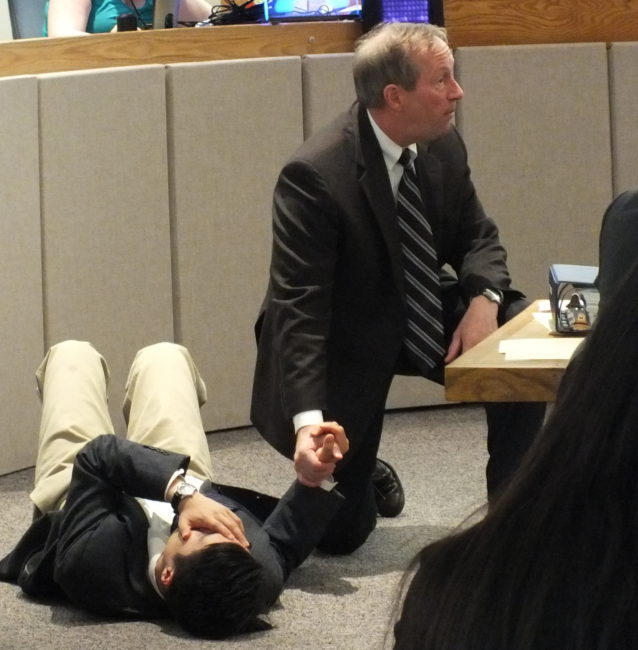 Attorney Mark Choate (right) recreates the murder of Simone Kim and its immediate aftermath during closing arguments to the jury on Thursday. Attorney Jon Choate portrays the wounded Kim. (Photo by Matt Miller/KTOO)