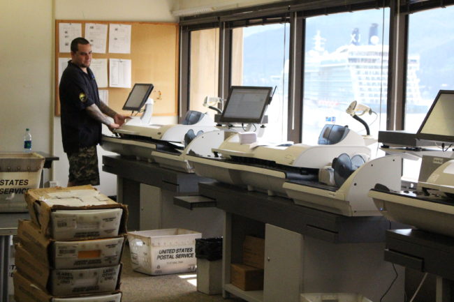 Jeremy Duncan runs letters through a postage machine  at the State Office Building. (Photo by Elizabeth Jenkins) 