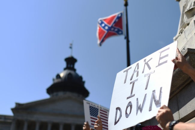Protesters hold a sign Tuesday during a rally to take down the Confederate flag at the South Carolina Statehouse in Columbia, S.C. Rainier Ehrhardt/AP