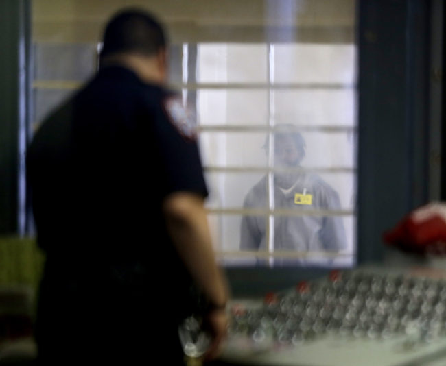 A prisoner behind bars and thick plastic looks at a corrections officer in an enhanced supervision housing unit on Rikers Island in New York. Seth Wenig/AP