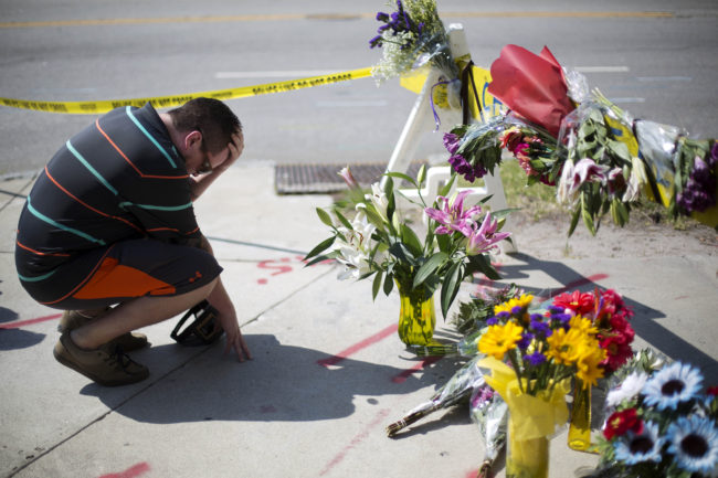 Noah Nicolaisen, of Charleston, S.C., kneels at a makeshift memorial for the victims of the shooting. Police apprehended the lone suspect during a traffic stop in Shelby, N.C., an almost four-hour drive from Charleston. (Photo by David Goldman/AP)
