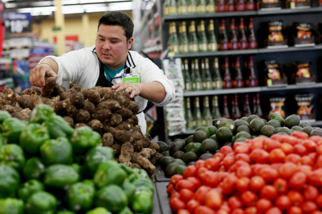 Wal-Mart employee Dayngel Fernandez stocks shelves in the produce department of a Miami store in February. Activists say the company's recent corporate policy changes don't address systemic labor and environmental problems. Joe Raedle/Getty Images