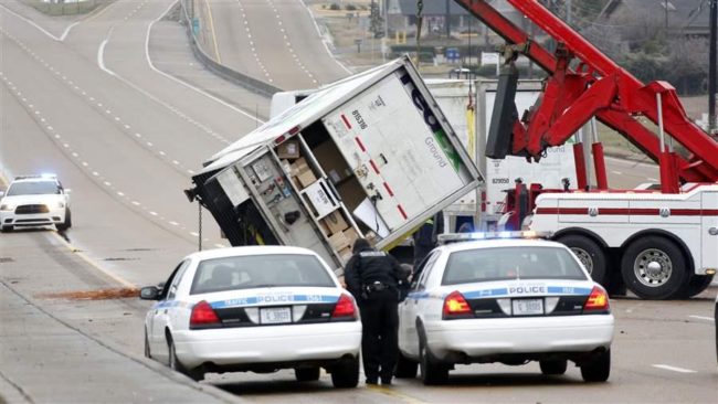 Police wait as a towing service attempts to right a trailer on Interstate 55 in Jackson, Miss. (AP)