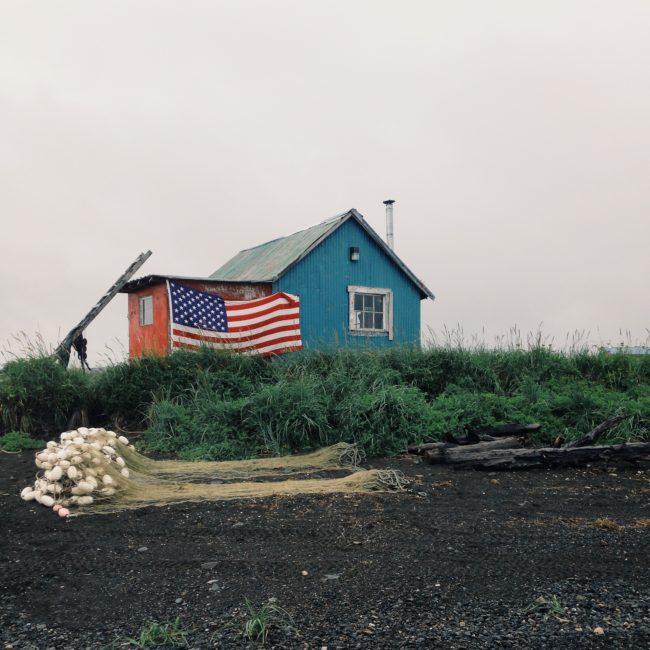 An American flag dons a fish camp cabin on Ekuk beach. (Photo by Matt Martin/KDLG)