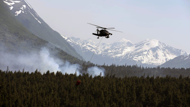 Some of Alaska's wildfires are dramatic: flames, vast plumes of smoke and firefighting battles. Here, on June 17, a helicopter releases hundreds of gallons of water onto the Stetson Creek Fire near Cooper Landing, Alaska. But even fires that look far quieter, like they're all burned out, can continue to smolder underground — and pose a dangerous threat to permafrost. Sgt. Balinda O'Neal/U.S. Army National Guard/AP