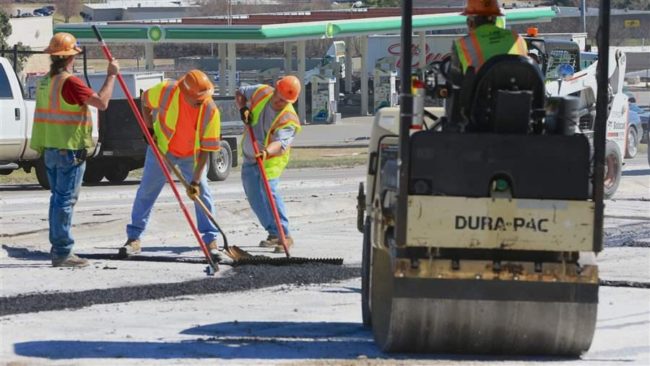 A road crew works next to a gas station on U.S. Route 275 in Omaha. Nebraska was one of eight states that increased gasoline taxes this year to pay for roads and bridges. AP