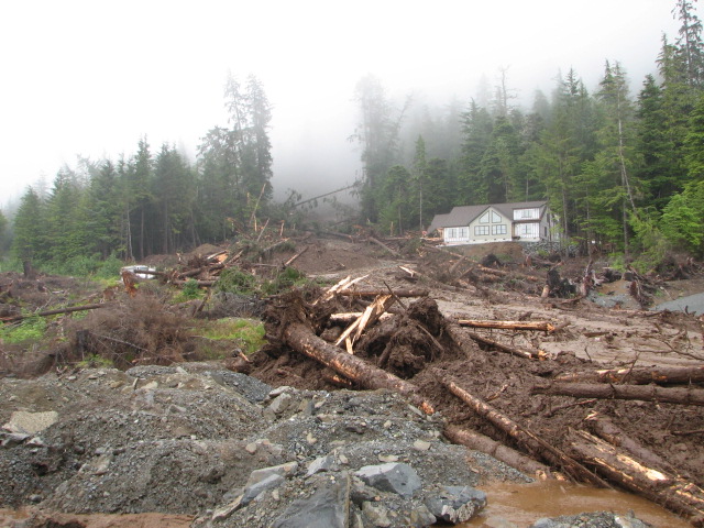 A new home under construction on Sitka’s Kramer Avenue was obliterated in the slide, Aug. 18, 2015. A neighboring home is unscathed. (Photo by Joel Curtis/National Weather Service)