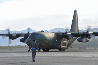 A Japanese Air Self-Defense Force airman directs a taxiing C-130H Hercules on Joint Base Elmendorf-Richardson, Alaska, Aug. 11, 2015. (Photo by Alejandro Pena/U.S. Air Force)