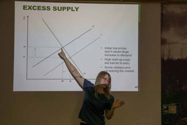 Carole Triem explains a slide about the supply and demand for marijuana retail stores. Triem, who's educated in economics and public policy, wrote a white paper on the topic. (Photo by Jeremy Hsieh/KTOO)