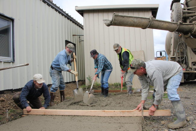 Paul Liedberg and Rick Dallmann level a new concrete slab while Jim Woolington, Bob Henry, Kendall Judge move the mud into place at the Dillingham Animal Shelter Aug. 19, 2015. (Photo by Molly Dischner/KDLG)