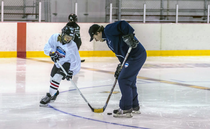 Juneau’s Taylor Bentley pokes the puck past Rocky Mountain Hockey School coach Vladan Chase during game of keep away to open one of the camp’s sessions at Treadwell Ice Arena. (Photo by Steve Quinn)