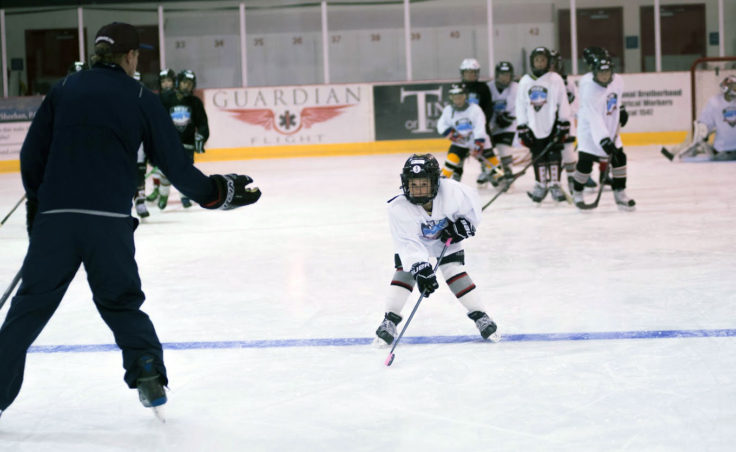 Macabee Brna focuses on a skating drill while Rocky Mountain Hockey School coach Billy Barto encourages him. (Photo by Steve Quinn)