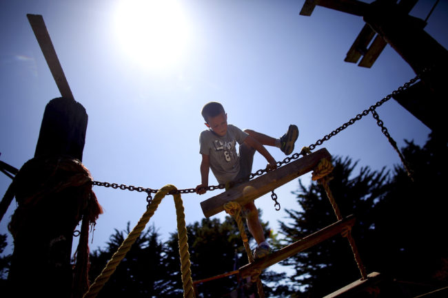 Seven-year-old Tyler Swenson uses a rope and a ladder to climb a wooden structure at the Berkeley Adventure Playground in California. David Gilkey/NPR