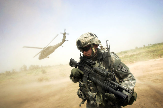 A U.S. soldier turns his back to the helicopter carrying Maj. Gen. Rick Lynch, the U.S. commander in central Iraq, as the chopper takes off from a patrol base south of Baghdad, in 2007. A surge in U.S. troops that year changed the course of the war and helped stabilize Iraq, at least temporarily. David Furst/AFP/Getty Images