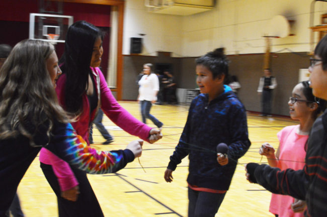 Hoonah students balance a small ball on two strings as a part of a team building exercise. (Photo by Lakeidra Chavis/ KTOO)