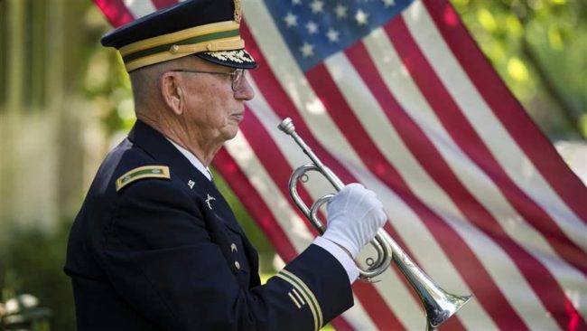 Retired Army Reserve Lt. Col. Philip Kowzan of Spokane, Washington, plays taps at a military honor funeral. States are competing to lower income taxes on military pensions to attract retirees. (AP)