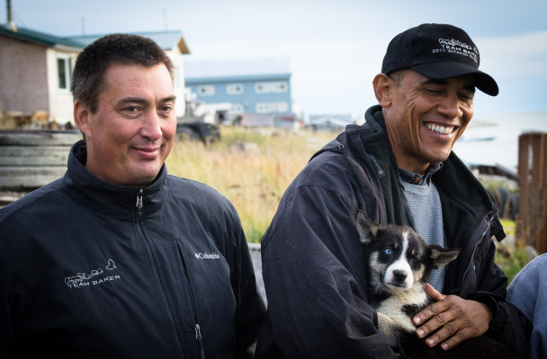 Iditarod musher John Baker meets President Barack Obama in Kotzebue, while Obama holds sled dog puppy Feather. (Photo by Matthew Smith/KNOM)