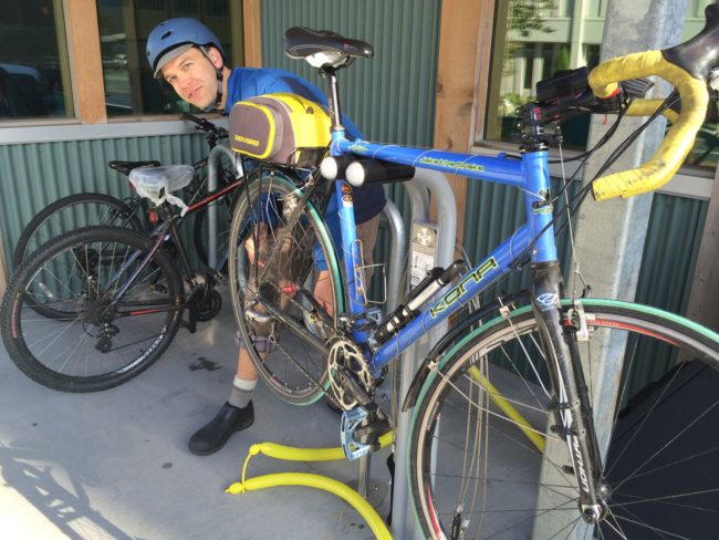 Corey McKrill uses the new bike station's stand, tools and pump to work on his bike. (Photo by Scott Burton/KTOO)