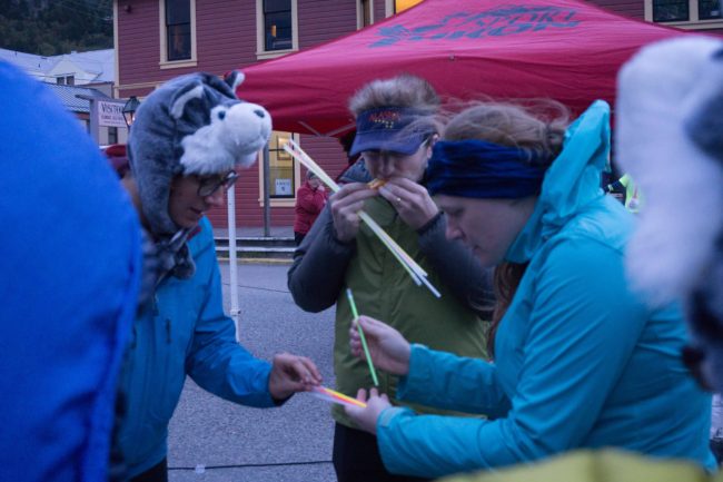 Wolf Taco's Sarah Gilman, Noah Bronstein and Allison Gillum distribute glow sticks near the starting line of the Klondike. (Photo by Jeremy Hsieh/KTOO)
