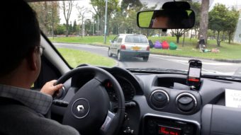 An Uber ride in Bogotá, Colombia. A phone running the Uber app is visible on the dashboard. (Creative Commons photo by Alexander Torrenegra)