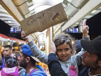 A migrant girl holds a sign expressing her love to Germany as she arrives at the train station in Saalfeld, central Germany, on Saturday. Hundreds of refugees arrived in a train from Munich to be transported by bus to an accomodation center. Jens Meyer/AP