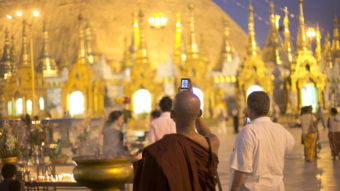 A Buddhist monk takes a photo on his phone at Shwedagon Pagoda in Yangon, Myanmar. Lauren Leatherby for NPR