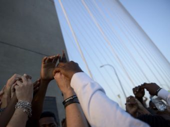 People interlock hands on the Arthur Ravenel Jr. Bridge in Charleston, S.C., a few days after nine black churchgoers were killed by a white shooter in June. A new PBS NewsHour/Marist poll finds attitudes about opportunities in the U.S. for blacks and whites contrast along racial lines. The poll will be discussed during PBS' America After Charleston broadcast Monday night. Brendan Smialowski/AFP/Getty Images