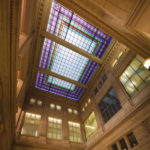 The multistory central hall has a stained-glass ceiling, echoed in smaller stained-glass windows throughout the building.