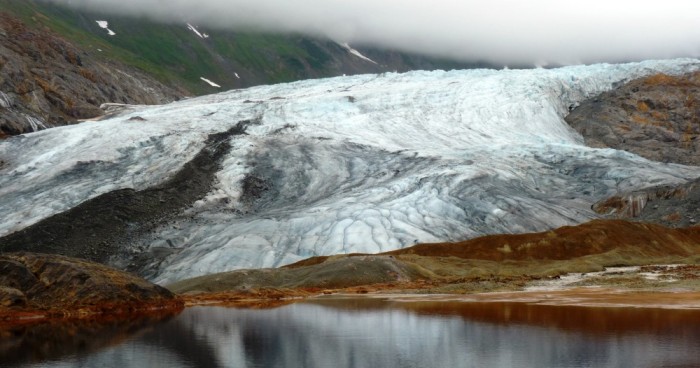 A glacier reflects in a naturally occurring pool of rusty, acidic water at the site of one of the KSM Prospect's planned open-pit mines. (Ed Schoenfeld/ CoastAlaska News).